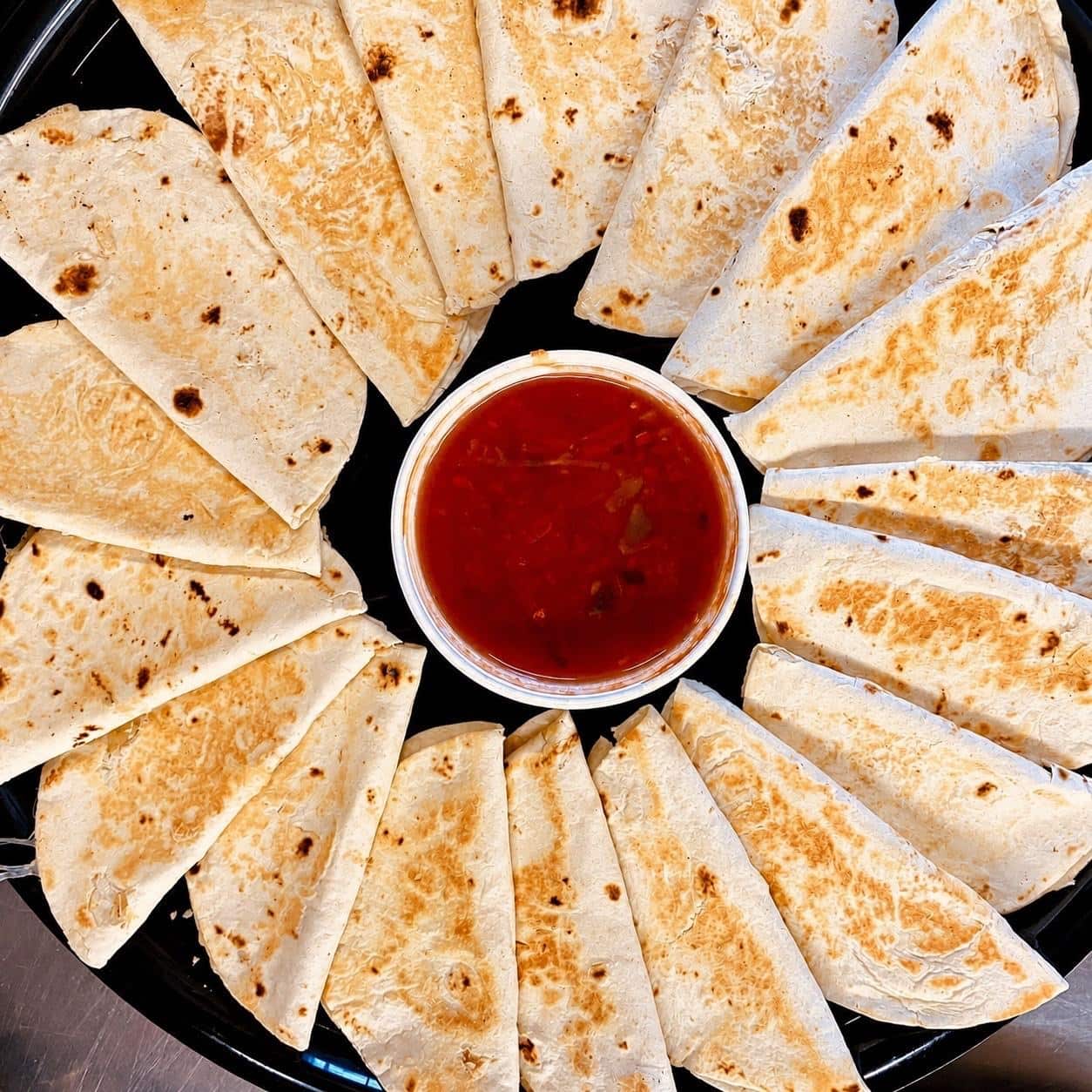 Quesadilla party tray arranged around a container of salsa